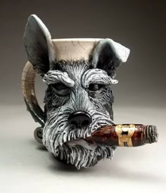 a ceramic dog head with a pipe in its mouth is sitting on a white surface