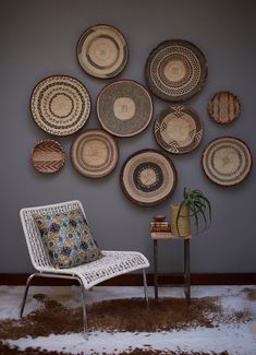 a white chair sitting in front of a wall with baskets on it