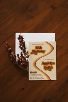 an orange and yellow business card sitting on top of a wooden table next to a plant