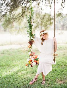 a woman sitting on a swing with flowers in her hair and holding onto the rope