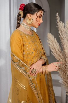 Luxury Mustard Yellow Pakistani Embroidered Salwar Kameez is a simplistic outfit in a mustard shade is crafted on raw silk. The artfully composed neckline, sleeves and hem features, golden embellishments, contrasting color embroidery and lace and tassel detailing, Embroidered Kameez: The beautiful Salwar Kameez comes in a beautiful mustard color and is emblazoned with intricate designs and fine details of embroidery. Floral designs, motifs, and hand-crafted details of sequins, stones, and tilla Transitional Gold Dress With Dabka Detail, Designer Gold Long Sleeve Dress, Gold Unstitched Suit For Eid, Gold Long Sleeve Dress For Designer Wear, Gold Raw Silk Dress With Dabka Work, Gold Saree Dress With Mirror Work, Gold Dabka Dresses In Chinon, Gold Dabka Dress For Designer Wear, Gold Chanderi Dress With Dabka Detailing