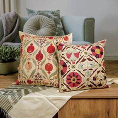 two decorative pillows sitting on top of a wooden table next to a blue couch and chair