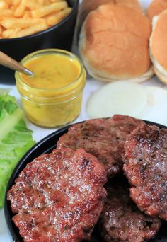 hamburger patties with mustard and lettuce on a plate next to other foods