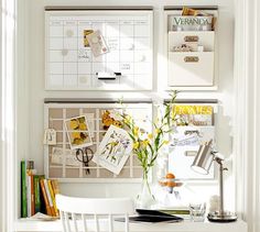 a white desk and chair in front of a wall with calendars on the walls