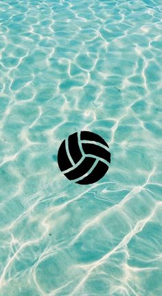 a black and white volleyball ball floating in the ocean water with ripples around it