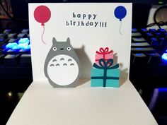 a happy birthday card with a totoro holding a gift box and a balloon