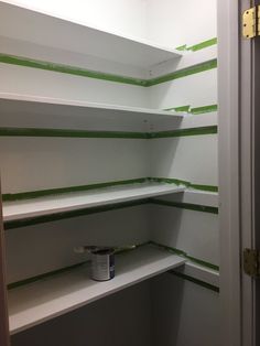 the shelves are painted white and have green stripes on them, as well as a paint can