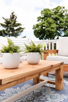 two planters sitting on top of a wooden table in front of a white couch