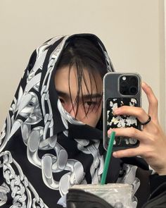 a woman wearing a black and white shawl taking a selfie with her cell phone