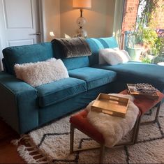 a living room with blue couches and pillows on the floor next to a window