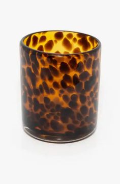 a brown and black glass candle holder on a white surface with an animal print pattern