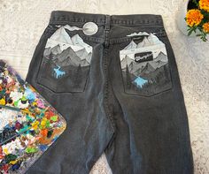 Unique hand painted 'Wrangler' jeans. We use restyled denim to create our one of a kind  designs! Painted with acrylic and textile paint, so the pants can be washed. I personally recommend hand washing them, or putting it on a gentle cycle in the washing machine. Please wash it with cold water and do not put in the dryer! Please keep in mind that having painted designs on pants unlike jackets can lead to more cracks, plus the design weathering quicker due to more movement and frequent washes! Je Painted Denim Jacket Mountains, Designs On Pants, Object Painting, Outfit Ideas Work, Spirit Week Outfits, Textile Paint, Painted Clothing