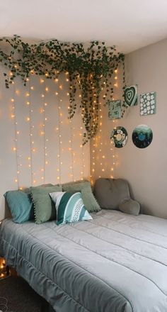 a bed sitting under a tree with lights on the wall and pillows in front of it