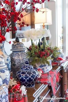 red and white flowers in blue vases sitting on a table next to a mirror