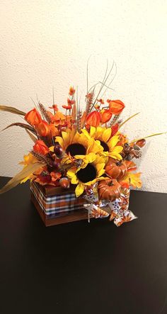 an arrangement of sunflowers and other flowers in a vase on a black table