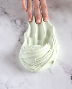 a hand holding a white frosted pastry on top of a marble counter