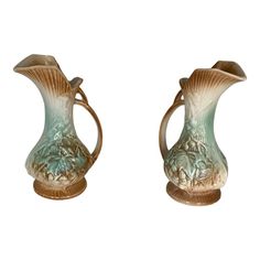 two green vases sitting side by side on top of each other, one with a handle