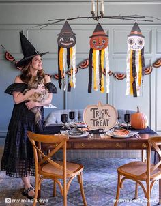 a woman holding a cat in front of a table decorated with halloween decorations and streamers