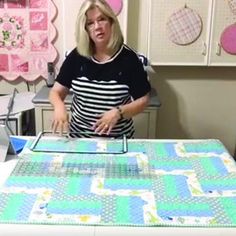 a woman standing in front of a table with a quilt on it