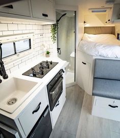 the interior of a camper with white walls and wood flooring, including a kitchen sink