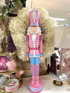 a pink nutcracker figurine sitting on top of a table next to white flowers