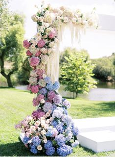 an outdoor wedding ceremony with flowers on the altar and water in the backgroud