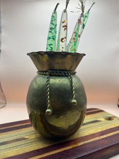 a green vase filled with candles on top of a wooden table