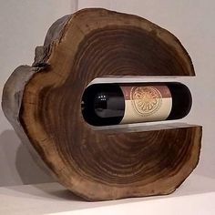 a bottle of wine sitting on top of a wooden stand next to a white wall