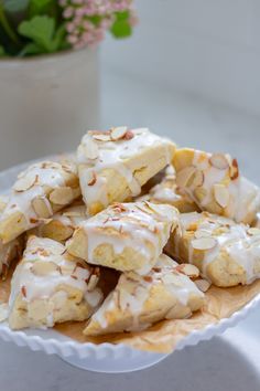 a white plate topped with sliced bananas covered in frosted icing next to a potted plant