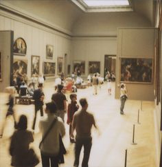 a group of people standing in a museum looking at paintings