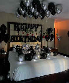 a bed topped with lots of black and silver balloons