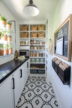 a kitchen with white cabinets and black counter tops next to a wall mounted chalkboard