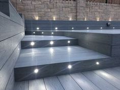 some steps with lights on them in front of a brick wall and wooden flooring