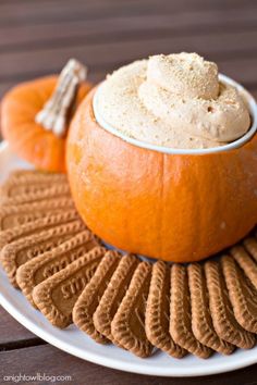 a plate topped with an orange and some crackers next to a bowl of whipped cream