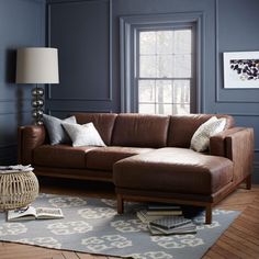 a living room with blue walls and brown leather couch in the corner, along with a rug on the floor