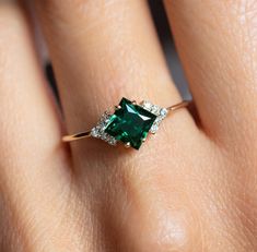 a woman's hand with an emerald and diamond ring