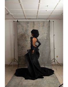 a woman standing in front of a backdrop wearing a black dress