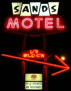 a neon sign that says sands motel and v2 block in rooms on the front