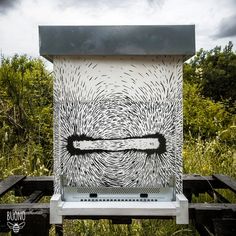 a white and black box sitting on top of a wooden table in front of trees