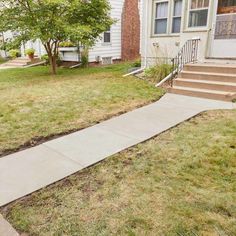 a sidewalk in front of a house with grass on the ground and steps leading up to it