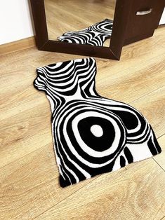 a black and white rug on the floor in front of a mirror with an abstract design