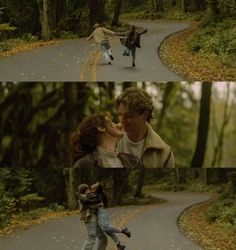 two people walking down a road in the woods and one is kissing another person's face