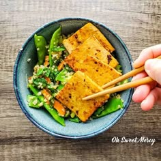 someone holding chopsticks over a bowl of food