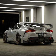 the rear end of a white sports car parked in a parking garage