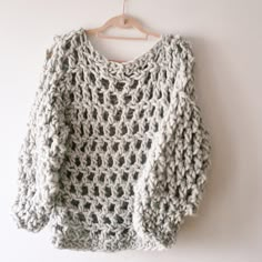 a crocheted sweater hanging on a hanger