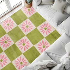 a green and pink rug on top of a white couch next to a potted plant