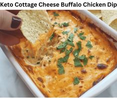 a hand dipping a tortilla chip into a casserole dish