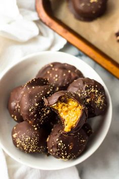 a white bowl filled with chocolate covered oranges