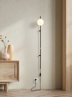 a floor lamp next to a table with vases on it and a light bulb plugged into the wall