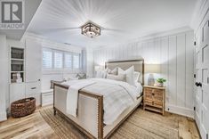 a bedroom with white walls and wood flooring has a large bed in the center